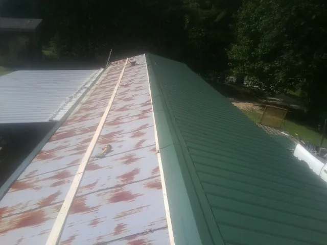 Old rusted panels beside newly installed green metal roofing — Wind Damage Roof Repair by Roofing Brothers in Crab Orchard
