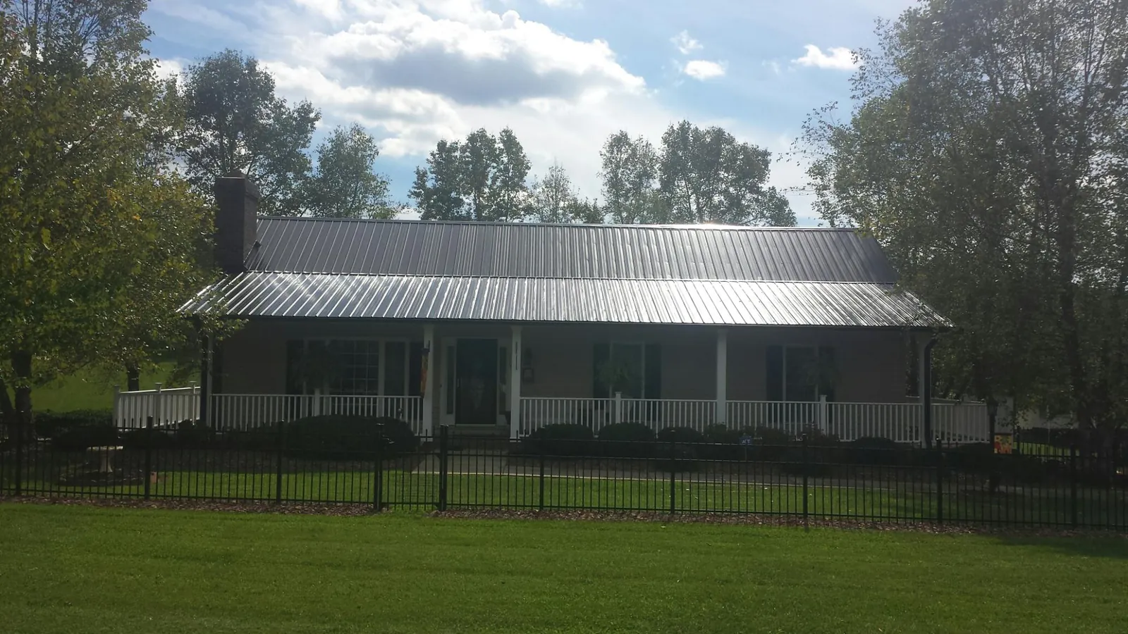 Gray metal roof on a brick ranch with a full width front porch — Gutter Guard Installation work by our crew in Crab Orchard