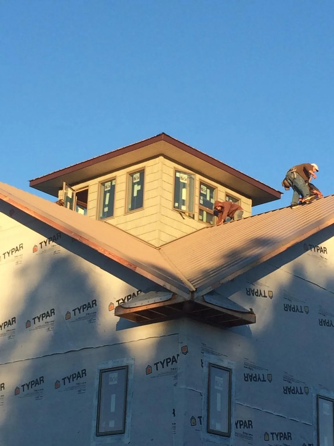 Roofers working around a rooftop cupola on a new metal roof at sunset — Roof Waterproofing in Crab Orchard by Roofing Brothers